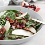 A bowl of spinach salad with fresh apples