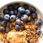 A bowl of yogurt, topped with granola, fresh blueberries, and nut butter.