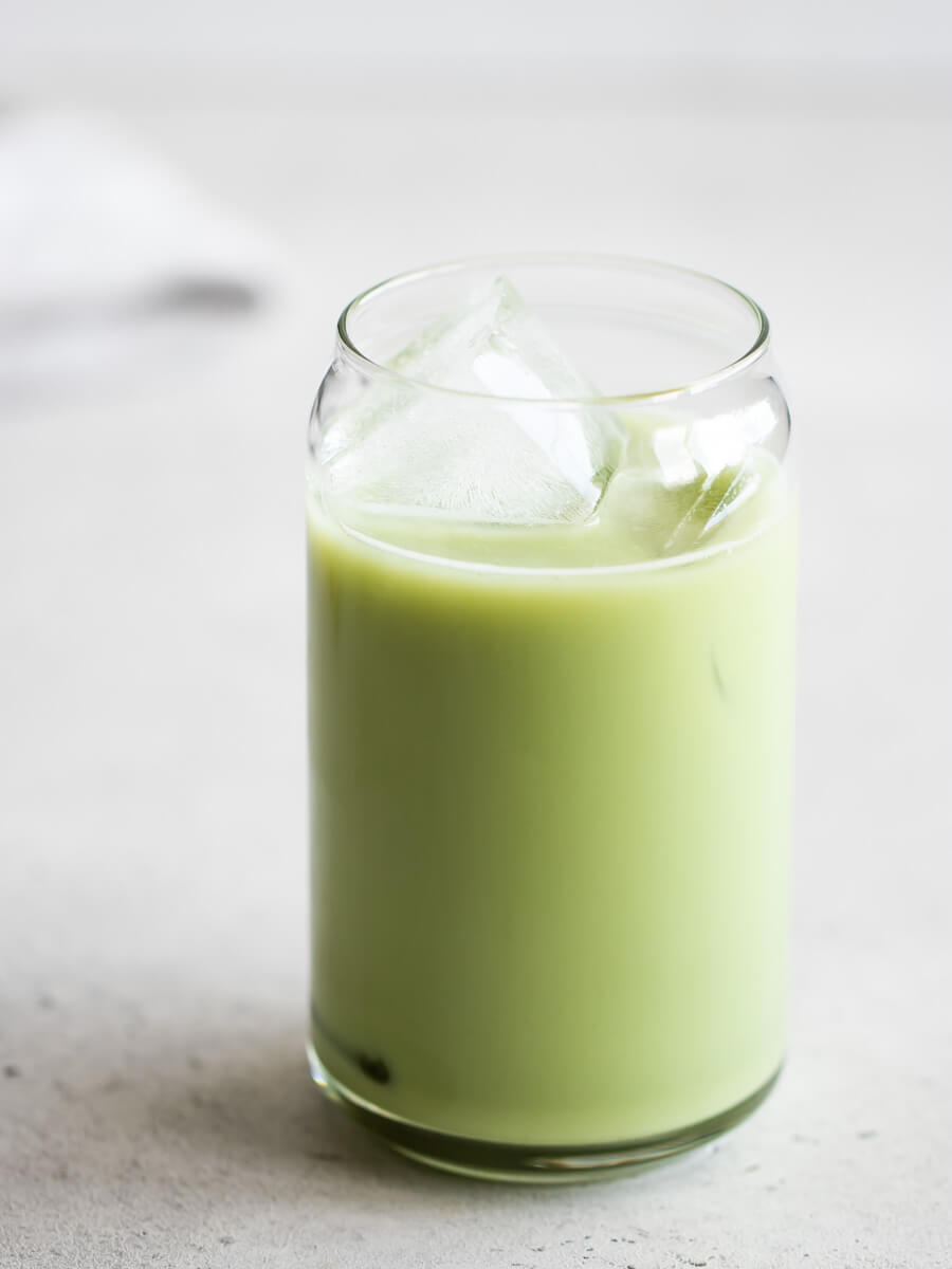 A glass of iced matcha latte, poured over ice.