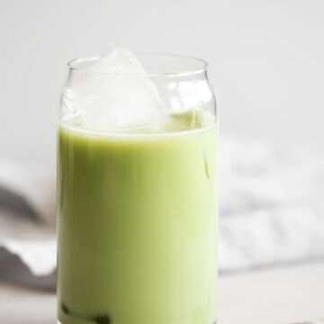 Glass of iced matcha latte with a spoon next to it.