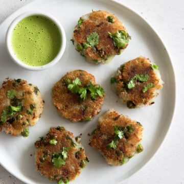A plate of aloo tikki with a bowl of chutney