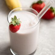 Glass of strawberry banana smoothie with a strawberry on top.