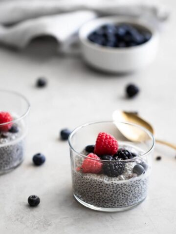 A glass filled with chia seed pudding with fresh berries.