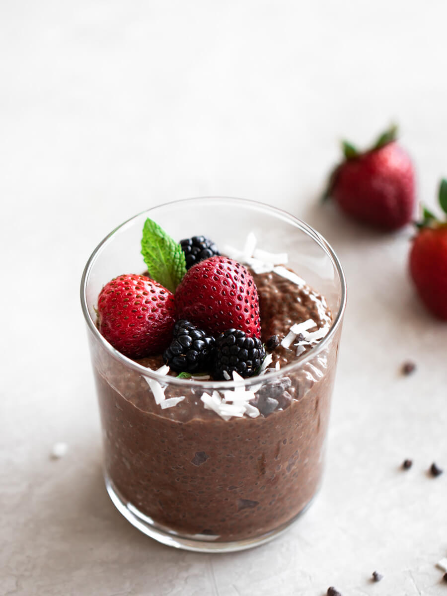 A glass of chocolate chia pudding with fresh blackberries and strawberries on top.