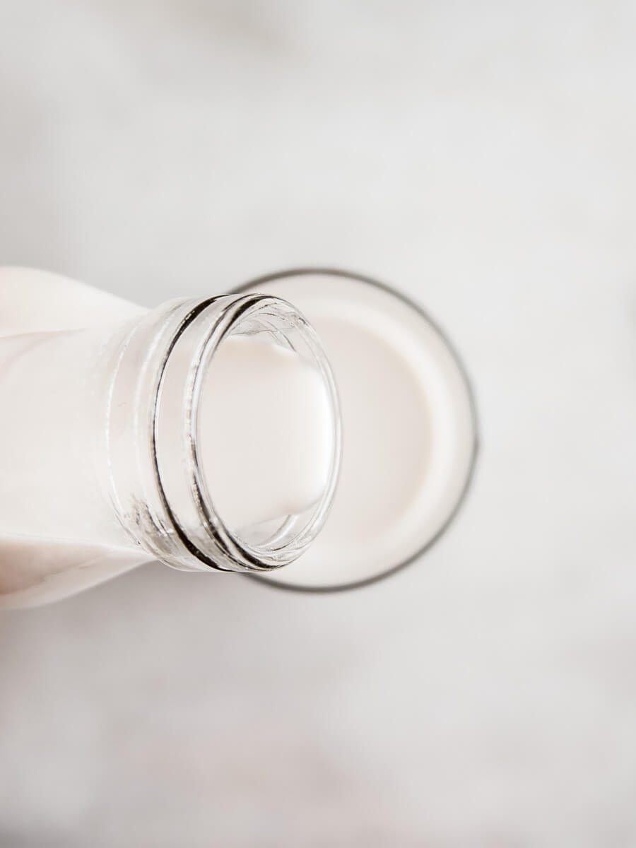 Almond milk being poured from a bottle into a glass
