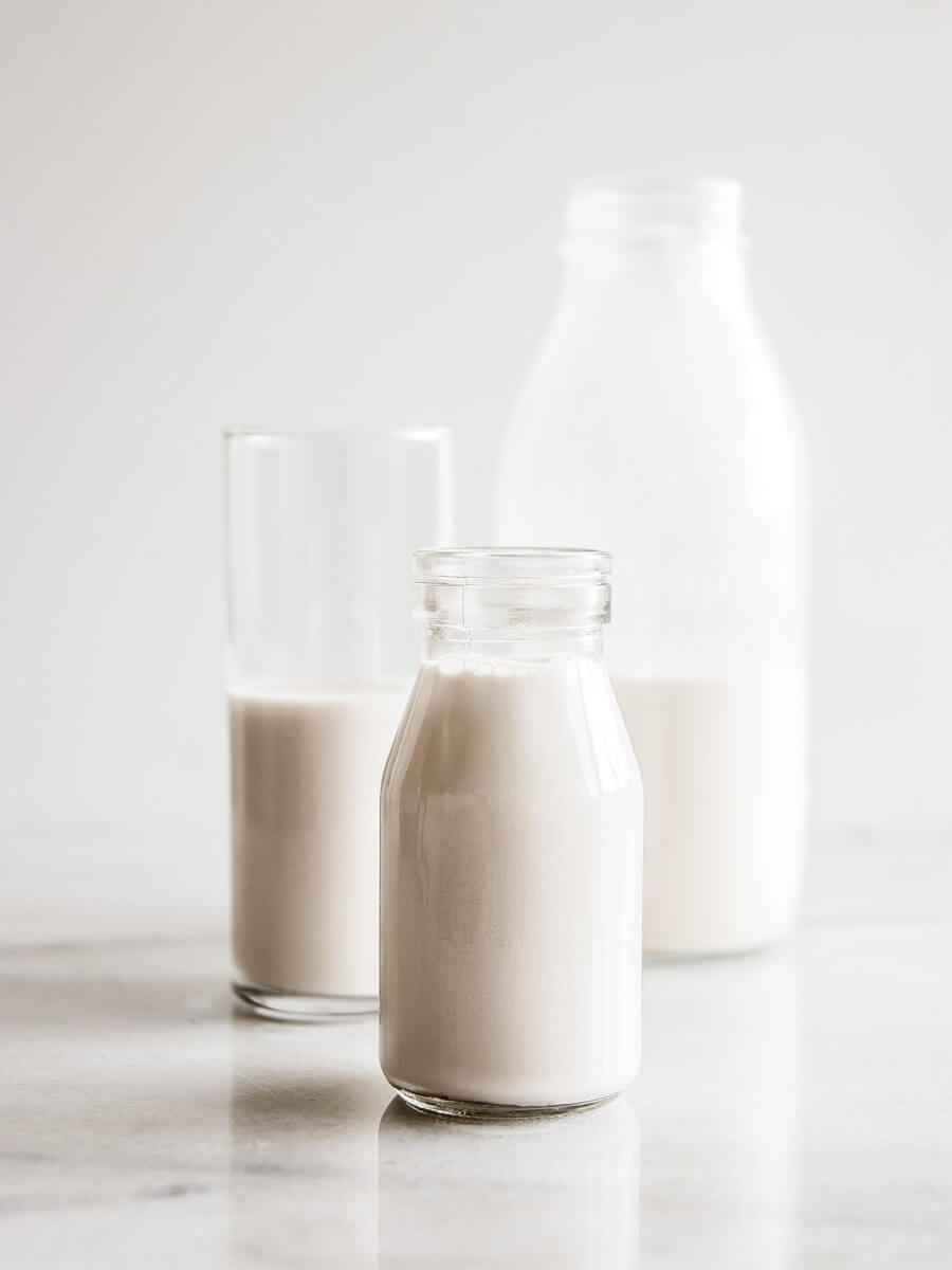 A jar of milk and two glasses of almond milk.