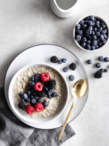 Bowl of overnight steel cut oats with fresh berries on the side.