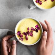 Hands holding cup of turmeric latte