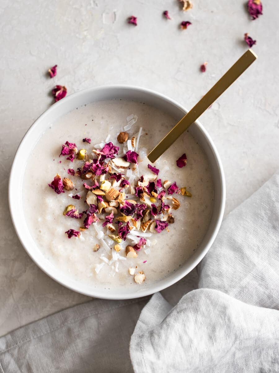 A bowl of Indian rice pudding, garnished with dried rose petals and nuts. 