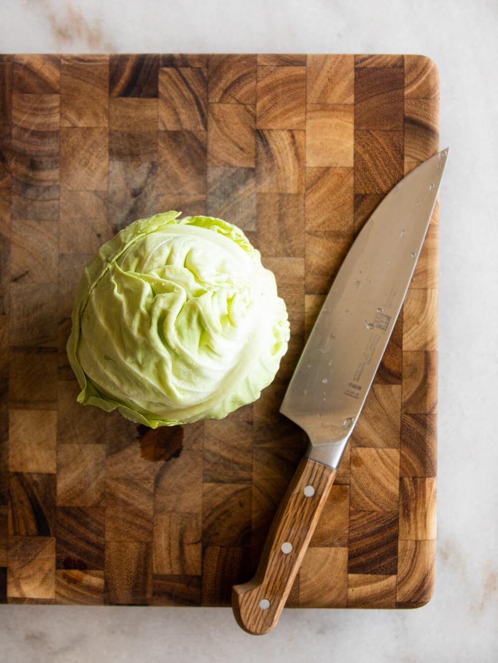 A head of cabbage sitting on a cutting board.