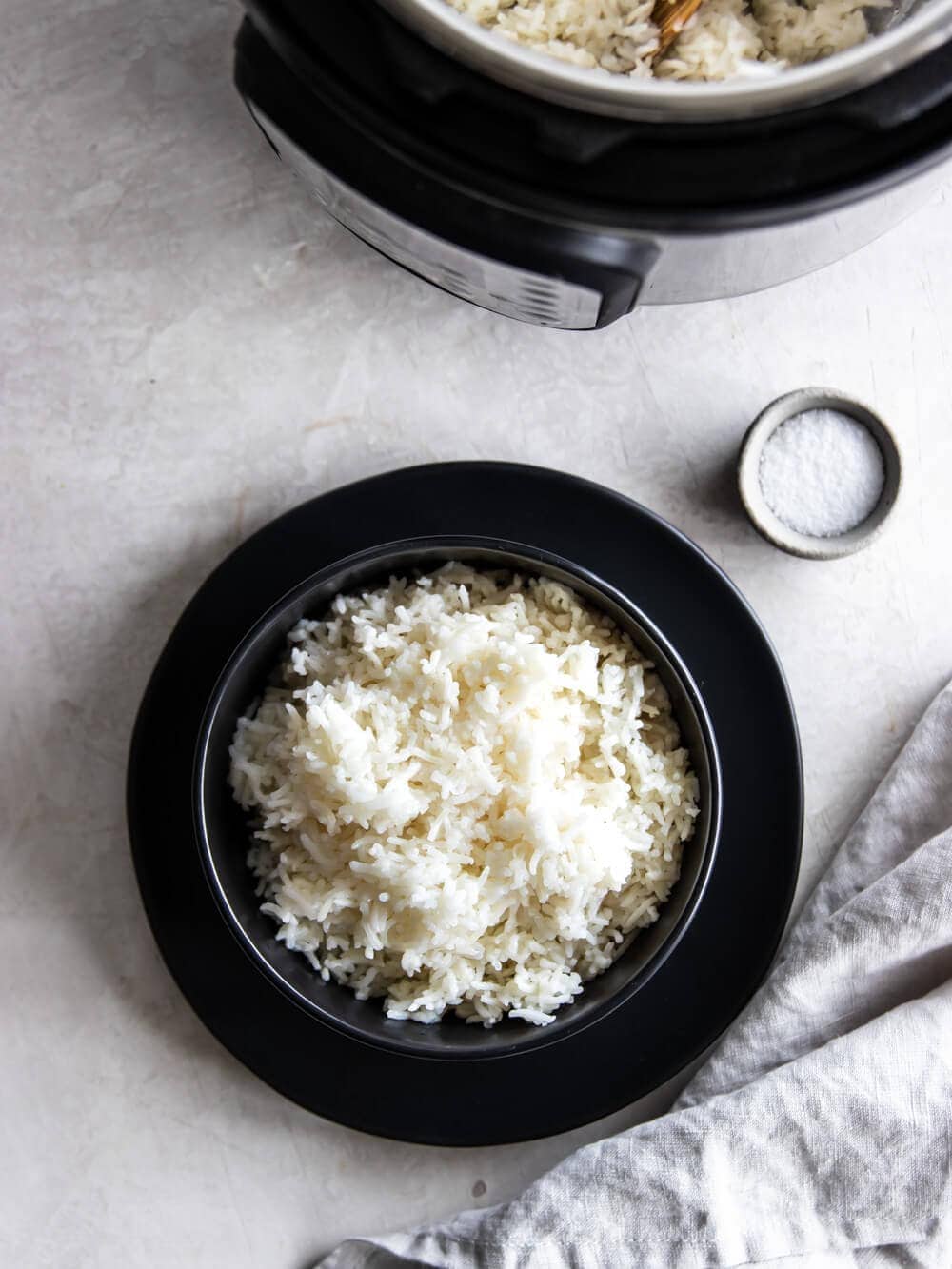 A bowl of rice sitting next to the Instant Pot and a small bowl of salt.