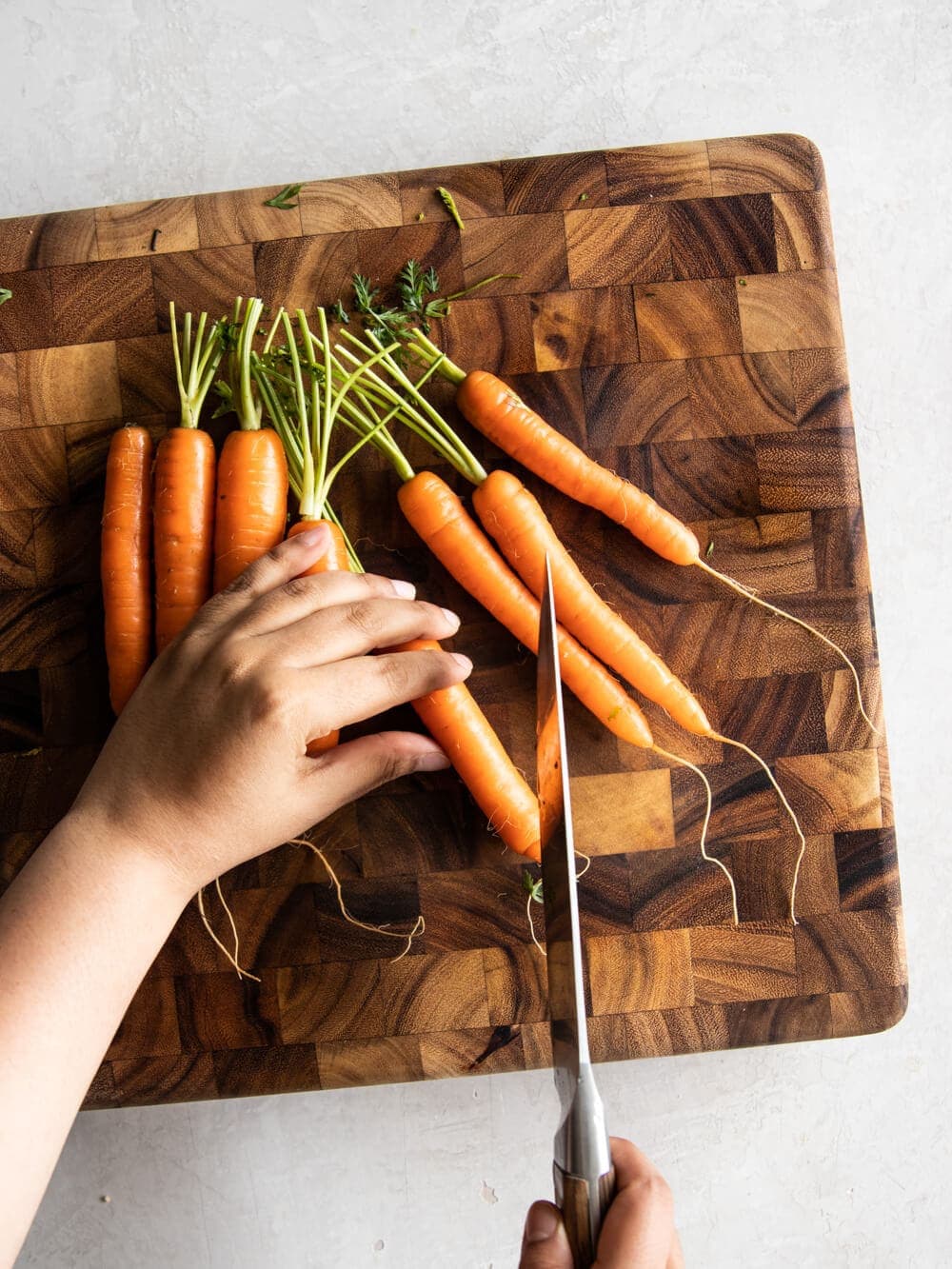 Hand cutting carrots on cutting board