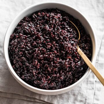 A bowl of black rice with a spoon in it