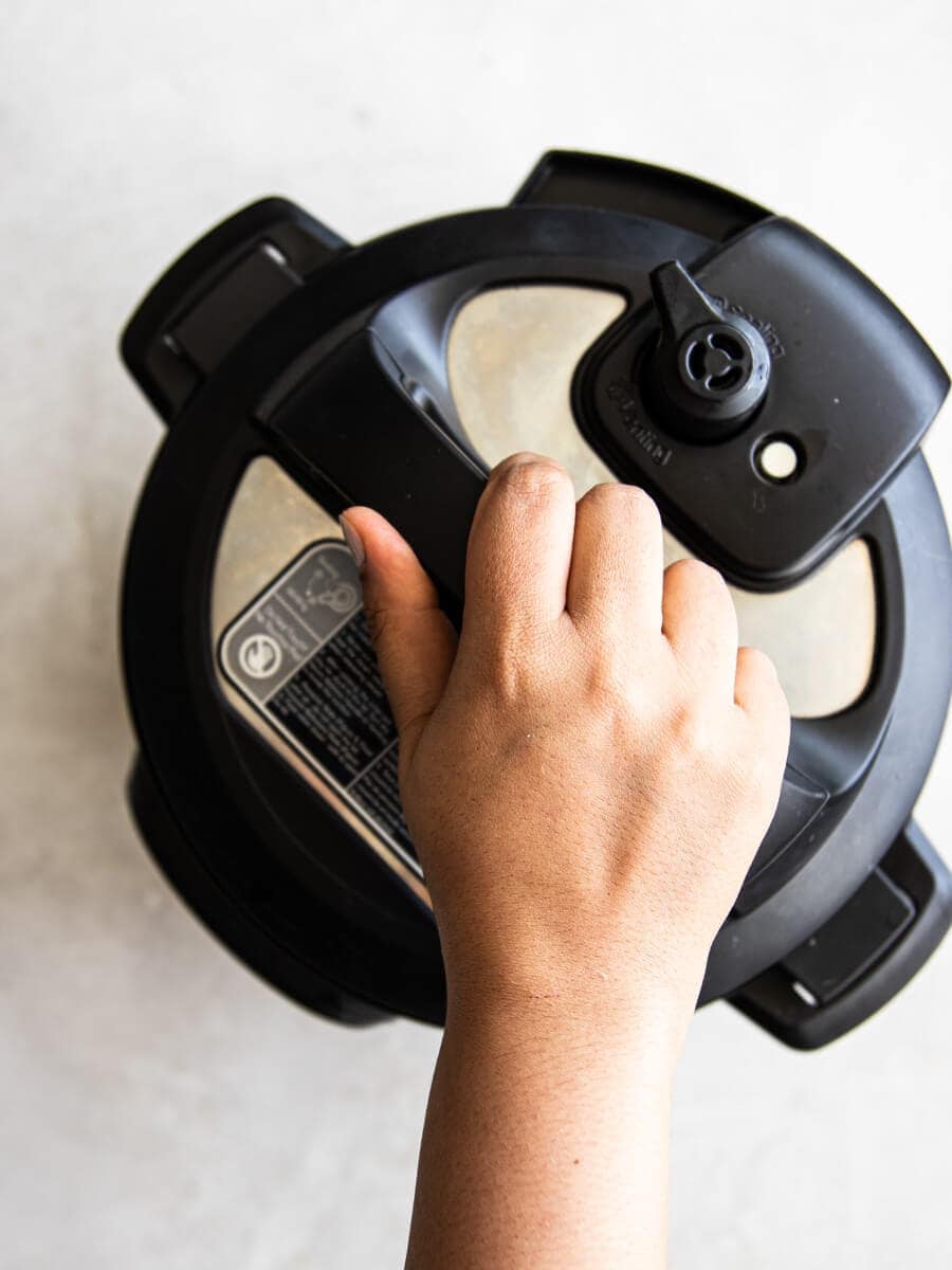 Hand closing the lid of the Instant Pot.