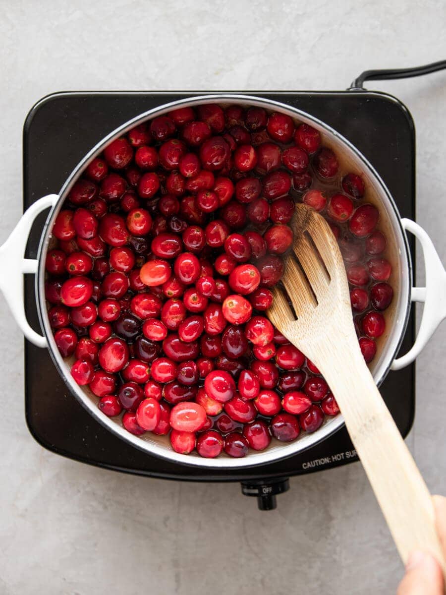Pot with fresh cranberries and wooden spoon
