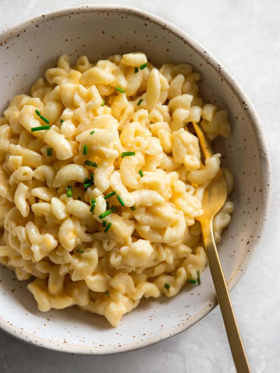 A bowl of mac and choose with a golden fork.