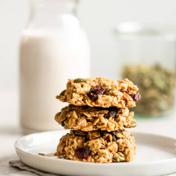 A stack of breakfast cookies with a glass of milk.