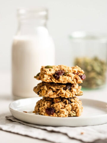 A stack of breakfast cookies with a glass of milk.