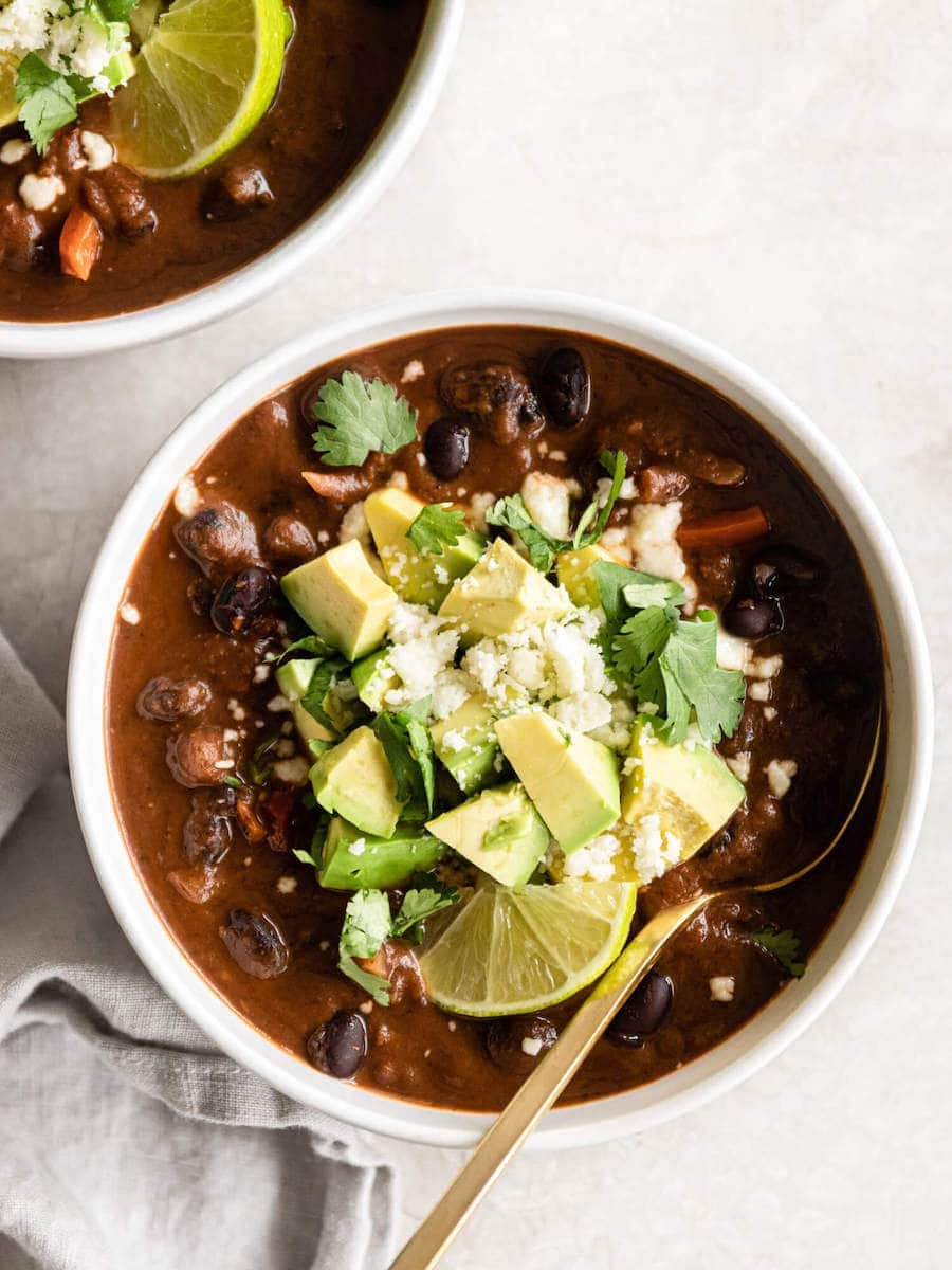 A bowl of black bean soup with fresh toppings.
