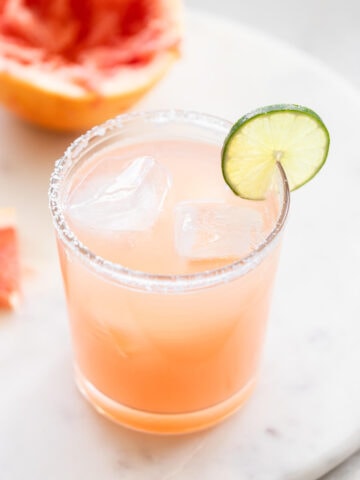 A grapefruit margarita with a slice of lime on the rim.