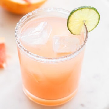 Glass of grapefruit margarita with a slice of lime.