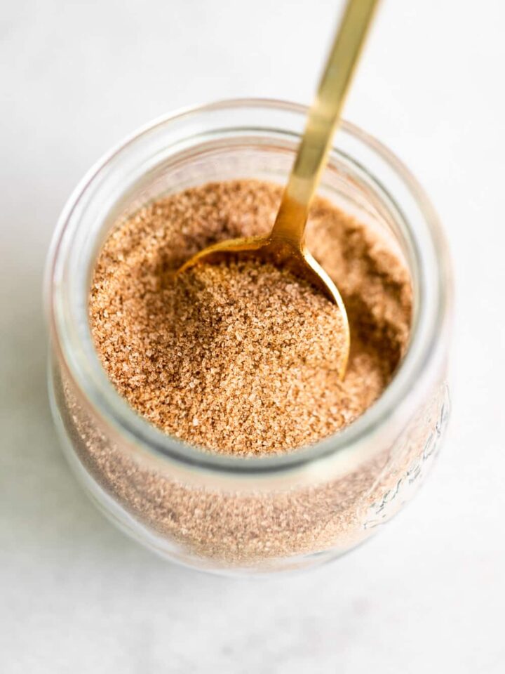 A jar filled with cinnamon sugar and a spoon.