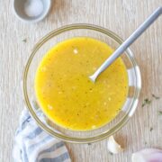 Apple cider vinegar dressing in a glass bowl with a kitchen towel.