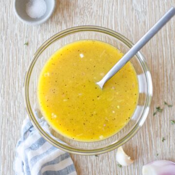 Apple cider vinegar dressing in a glass bowl with a kitchen towel.