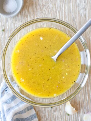 Apple cider vinegar dressing in a glass bowl with a kitchen towel.