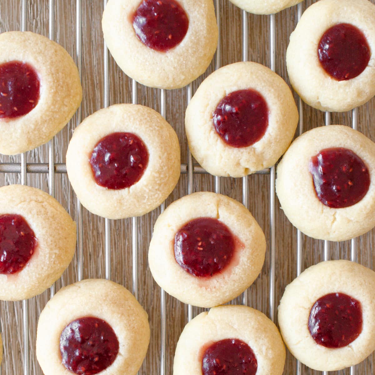 Baked raspberry thumbprint cookies on cooling rack.