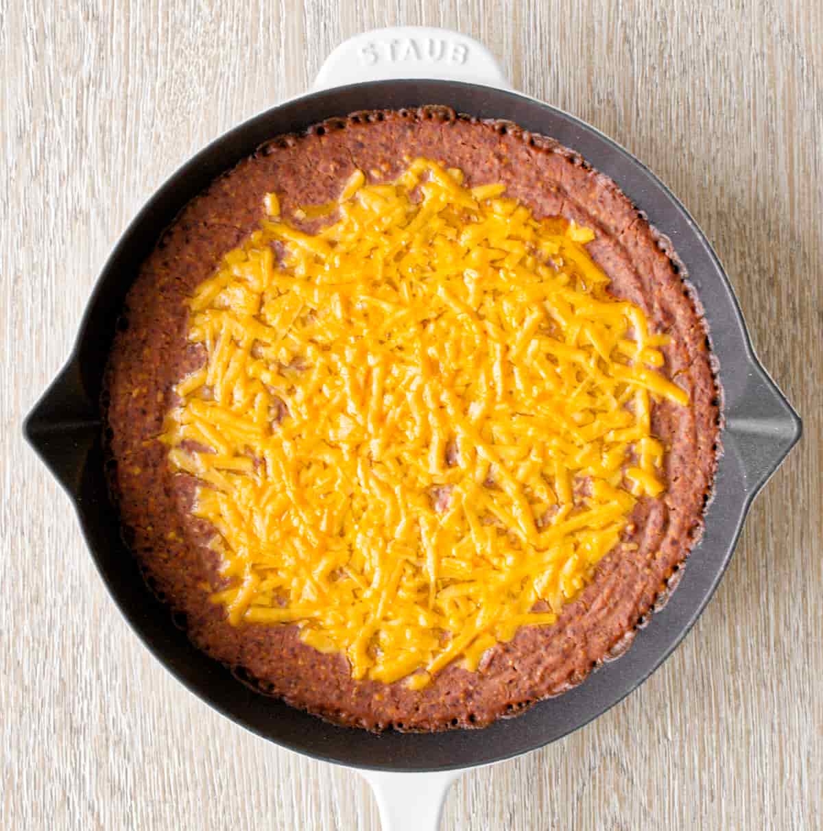 Baked black bean dip with melted cheddar cheese.