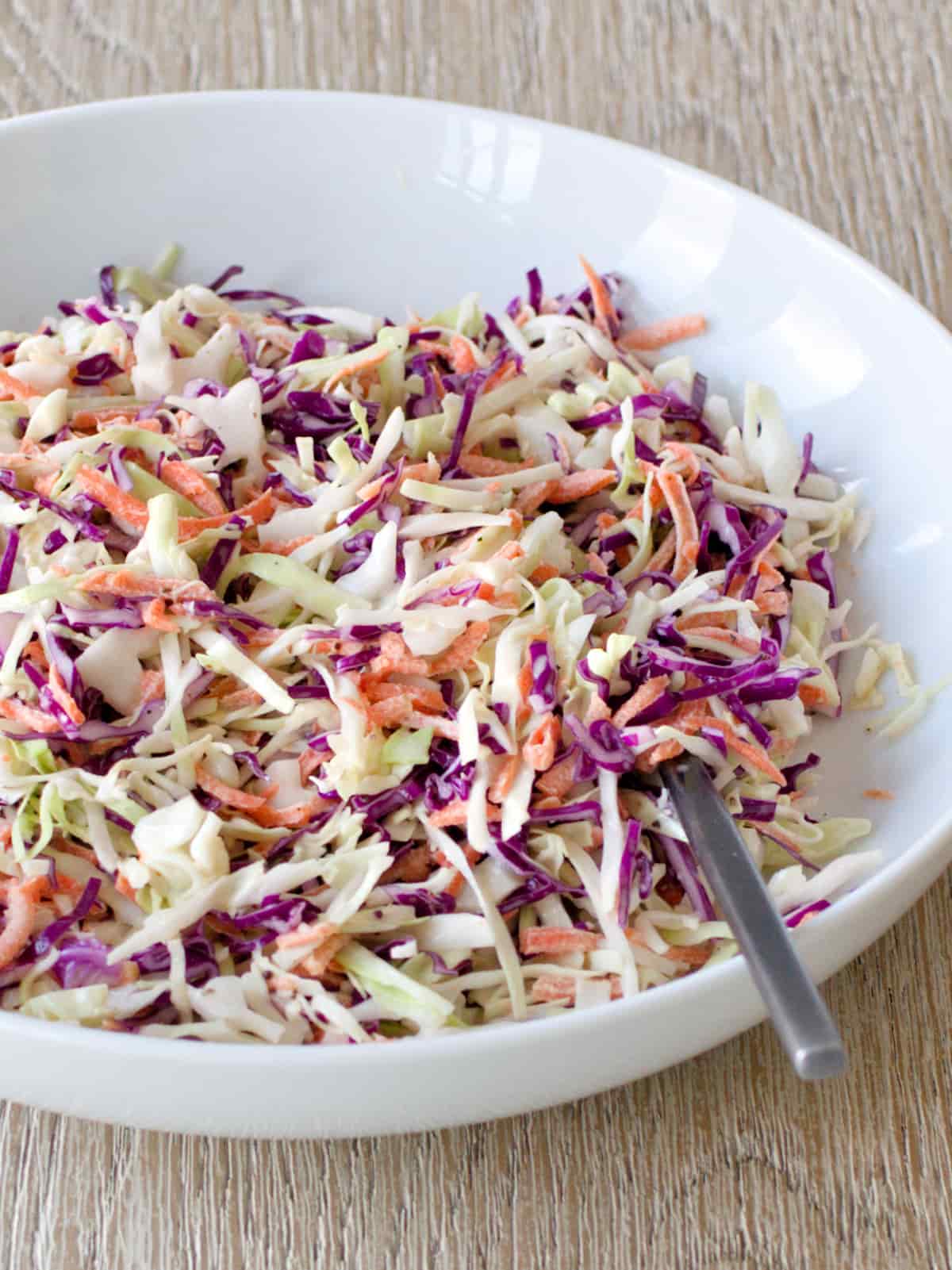 Coleslaw in serving bowl with serving spoon.