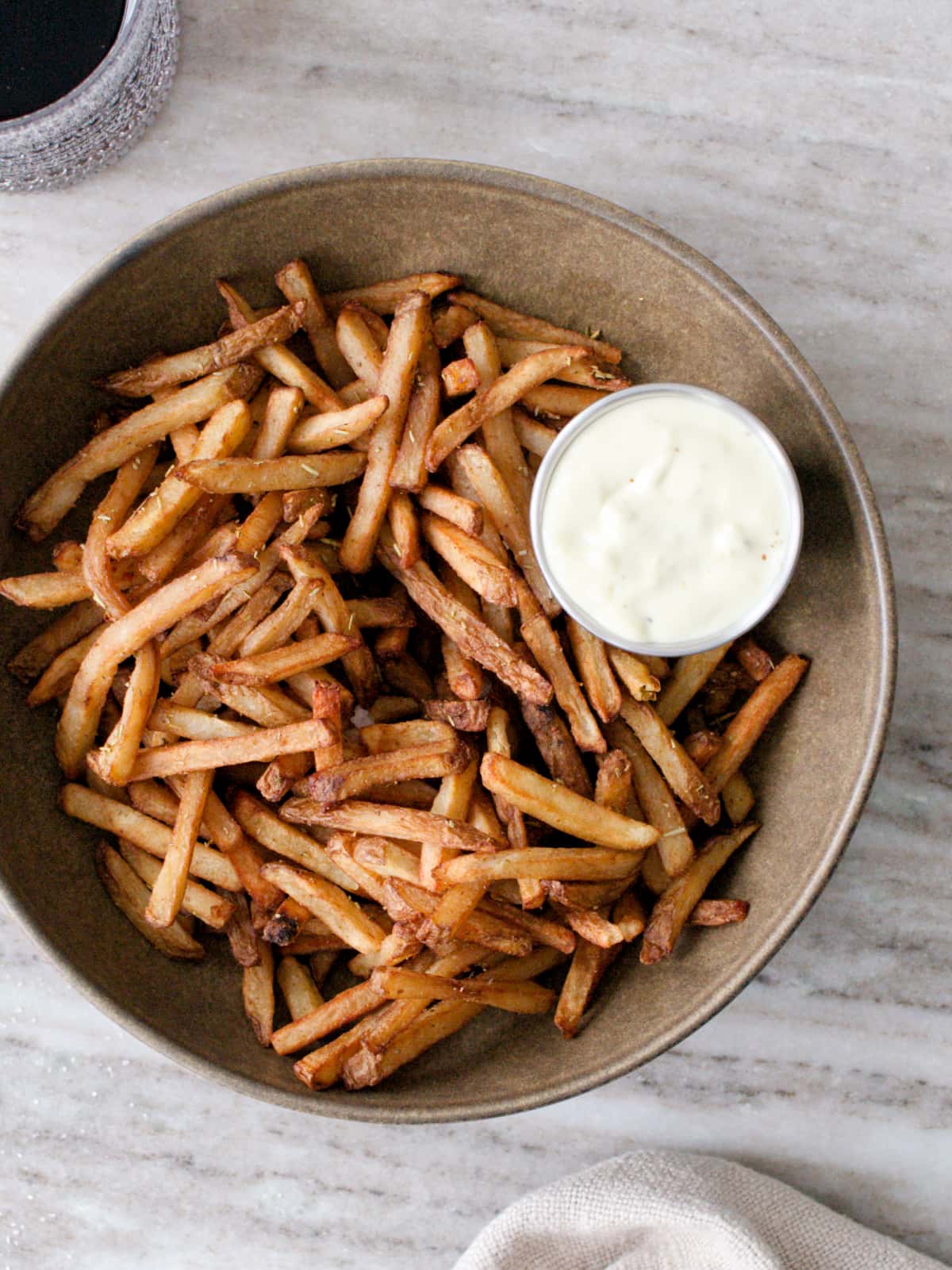 Large bowl filled with fries and small bowl of garlic mayonnaise.