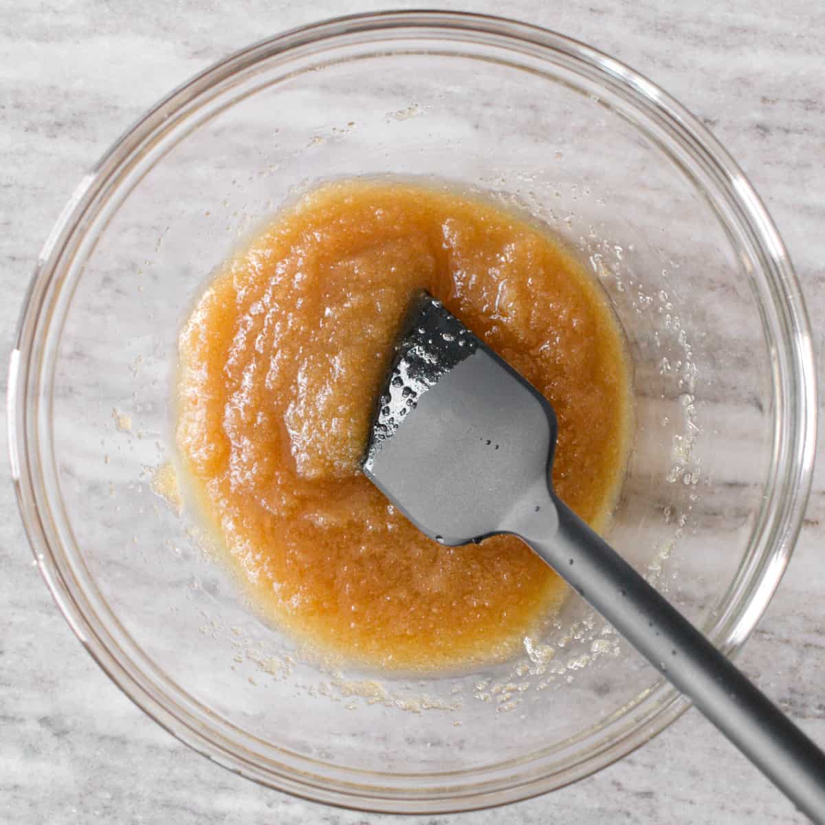 Mixed melted butter, brown sugar, and cane sugar in a medium bowl with a spatula.
