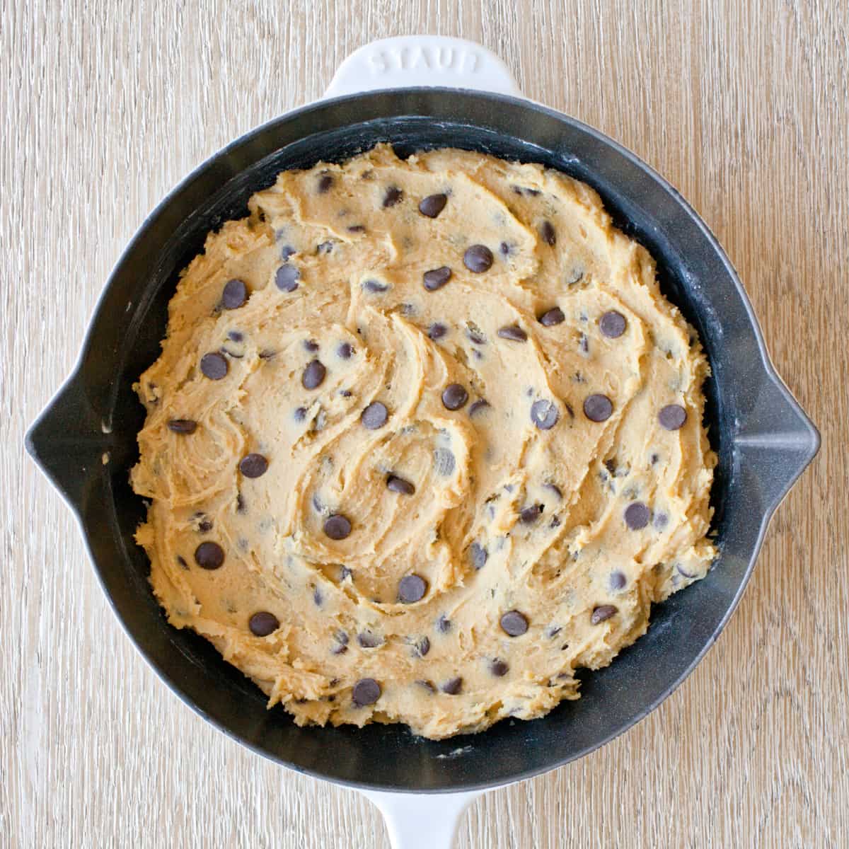 Chocolate chip cookie dough ready to be baked in skillet.
