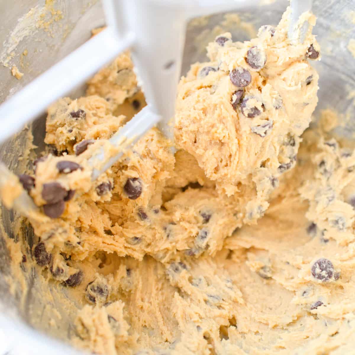 Cookie dough with chocolate chips in stand mixer bowl.