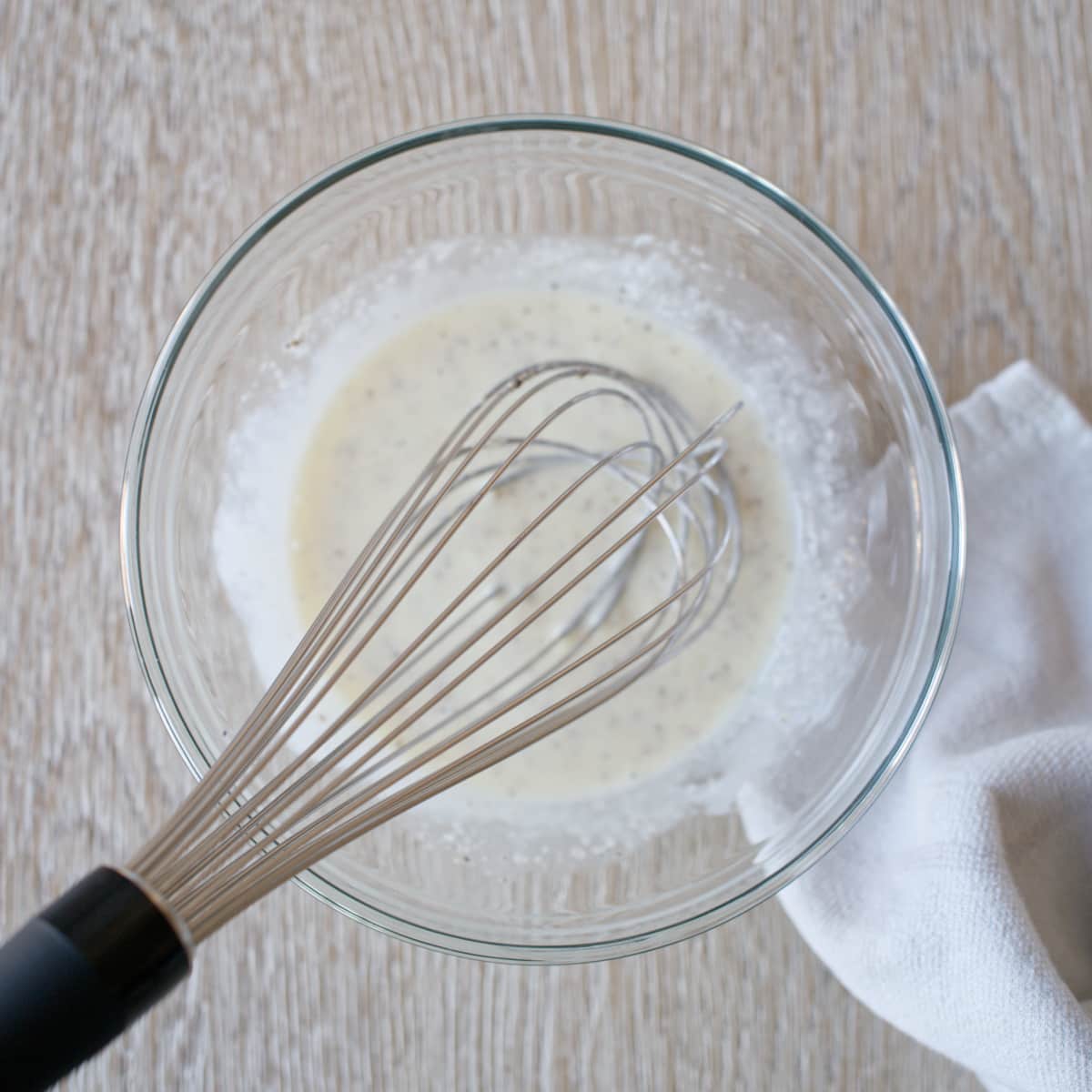 Whisking coleslaw dressing in a medium bowl.