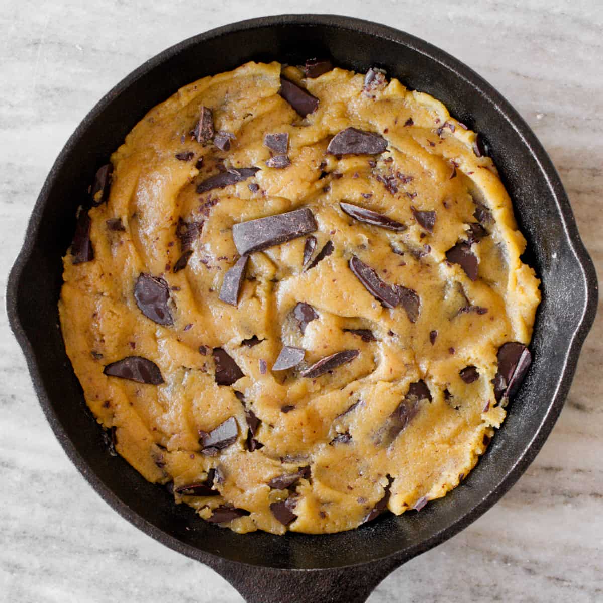 Cookie dough spread onto mini cast-iron skillet.