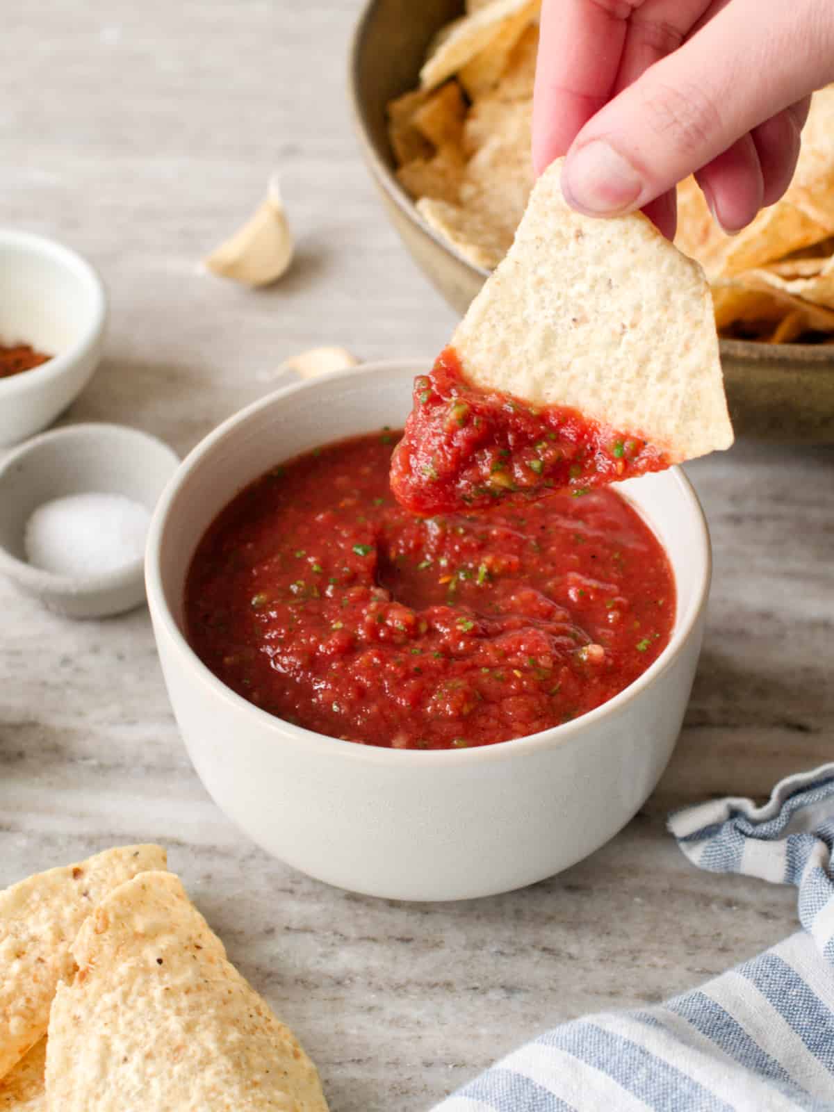 Tortilla chip dipping in bowl of homemade salsa.