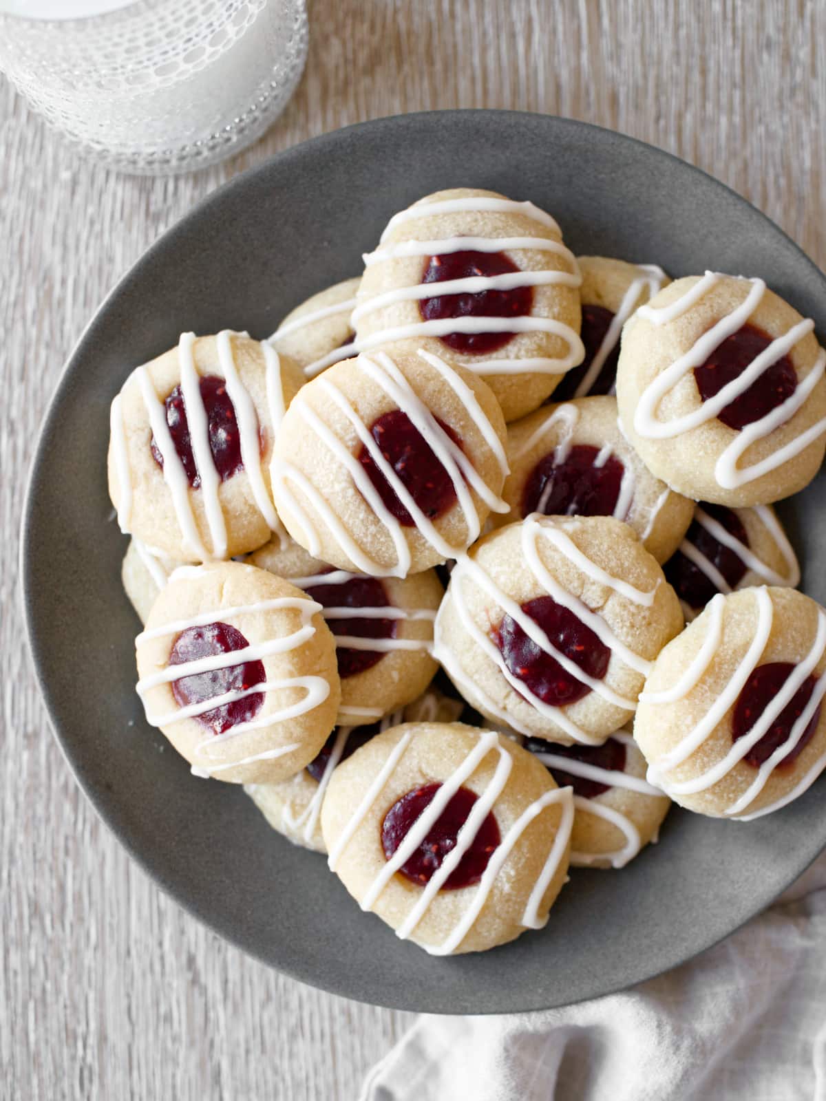 Plate full of raspberry thumbprint cookies and glass of milk.
