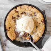 Mini skillet cookie with a scoop of ice cream and spoon.