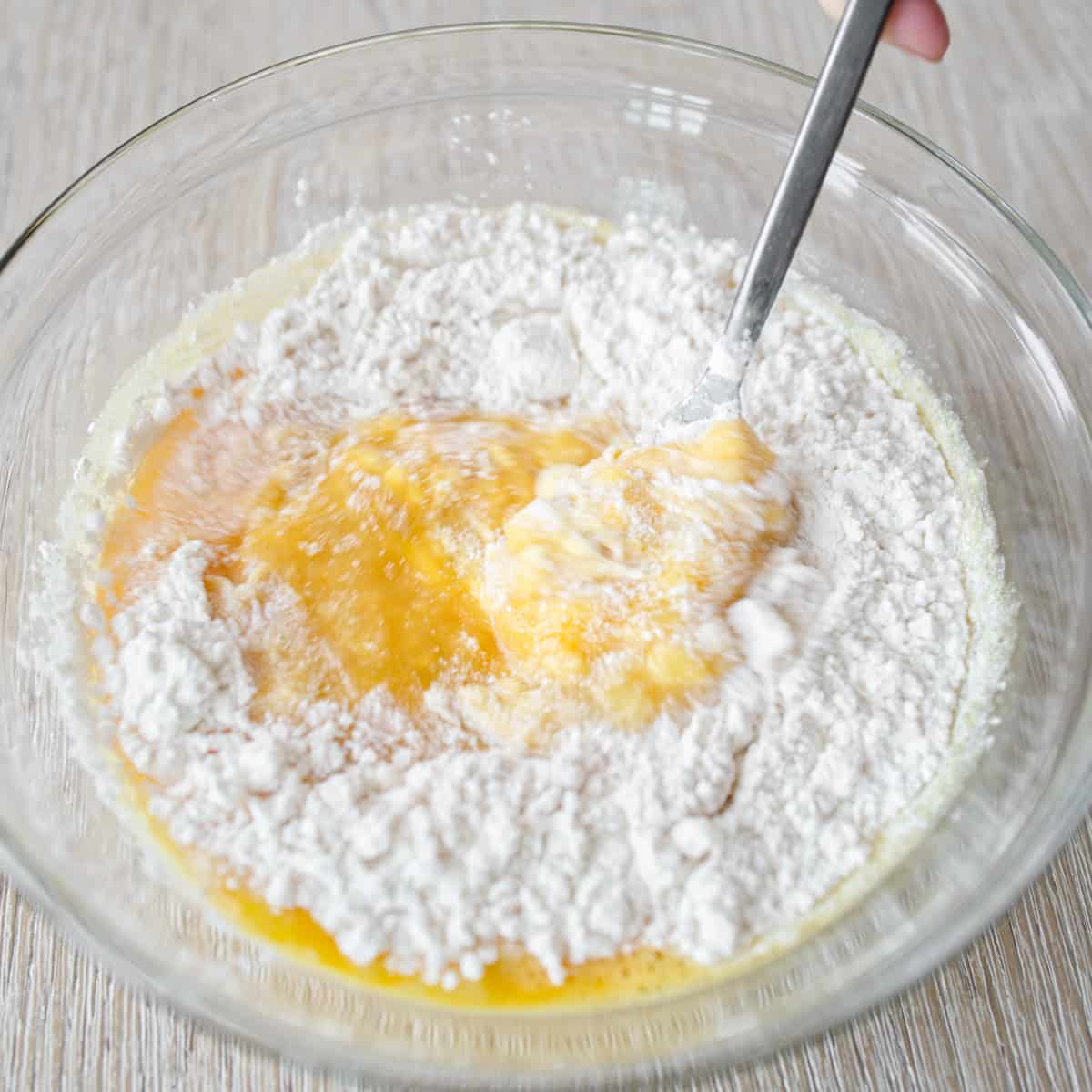 Mixing flour into mashed bananas and eggs.