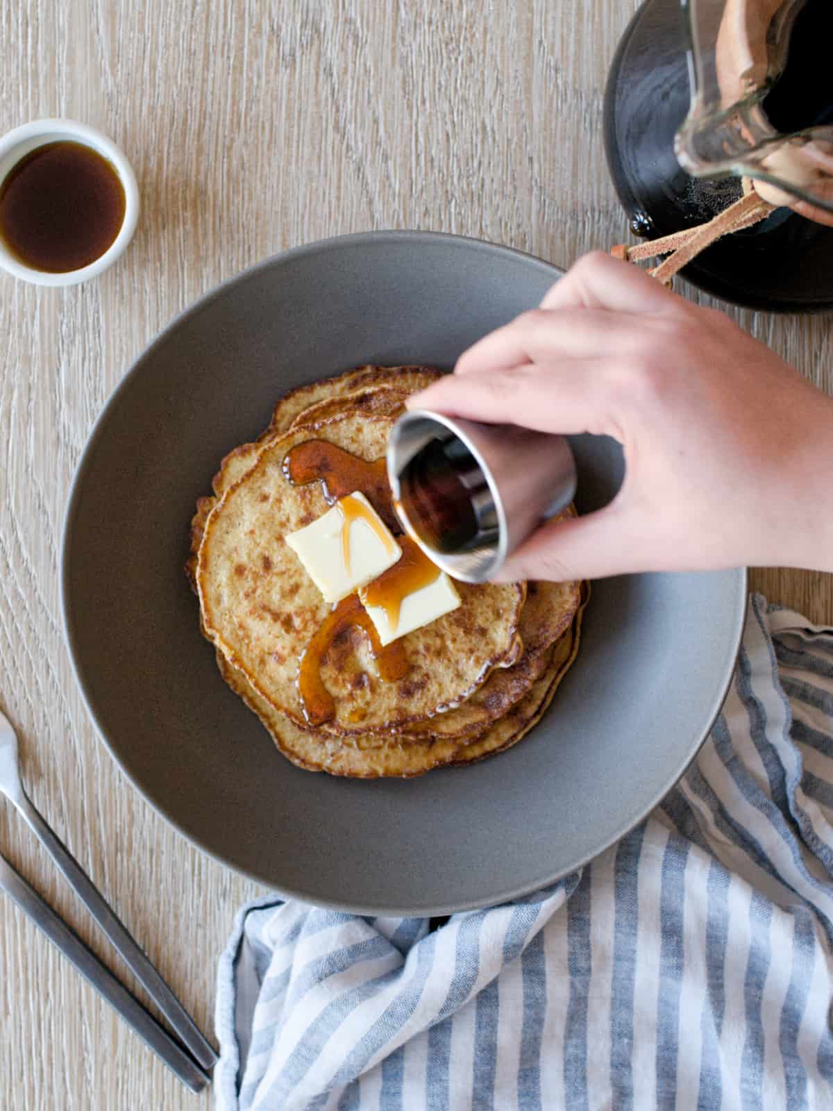 Pouring maple syrup on banana pancakes.