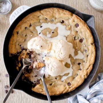 Skillet chocolate chip cookie with ice cream and two spoons.