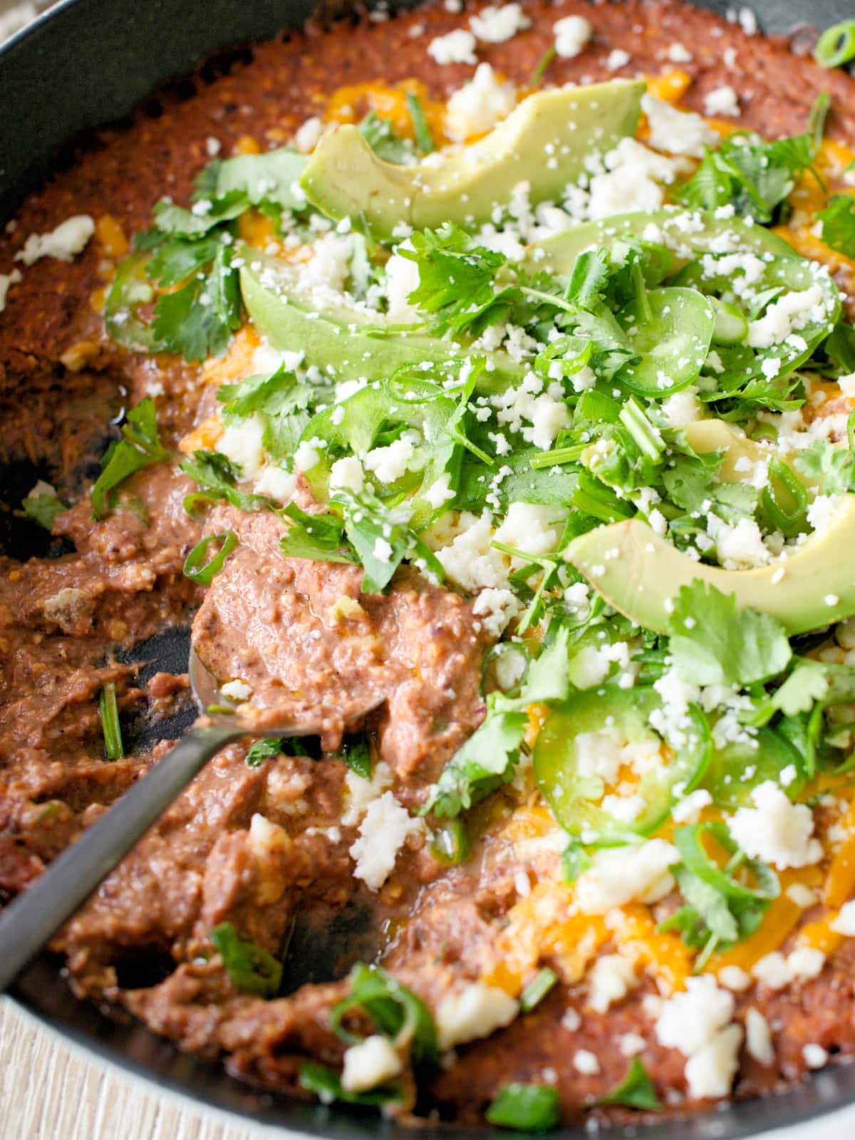 Spoon scooping black bean dip in skillet.
