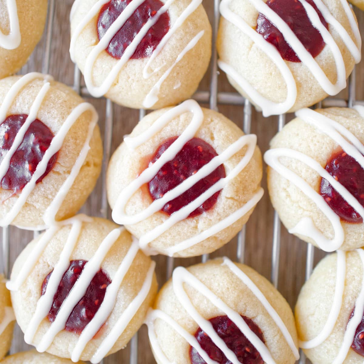 Baked raspberry thumbprint cookies drizzled with vanilla glaze.