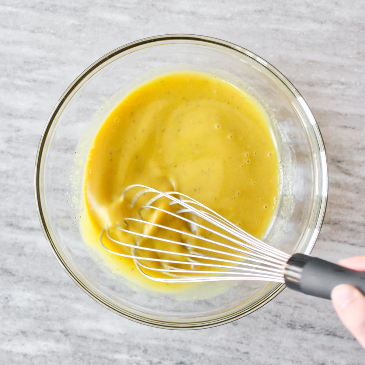 Whisking after adding olive oil to the dressing.