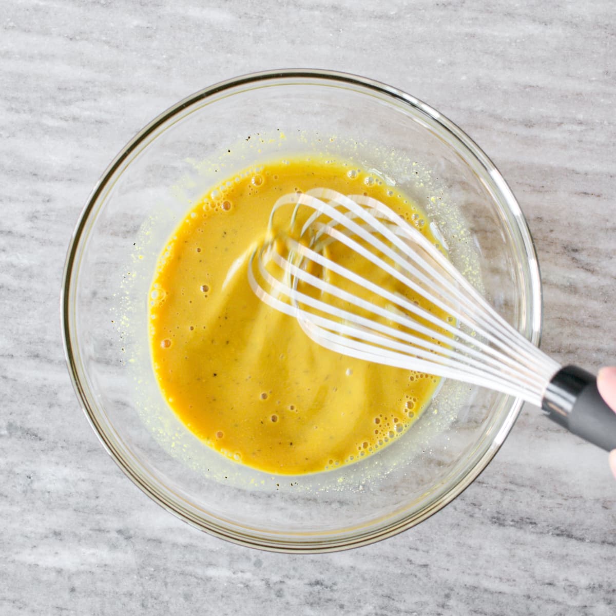 Whisking ingredients for honey mustard dressing in medium bowl.