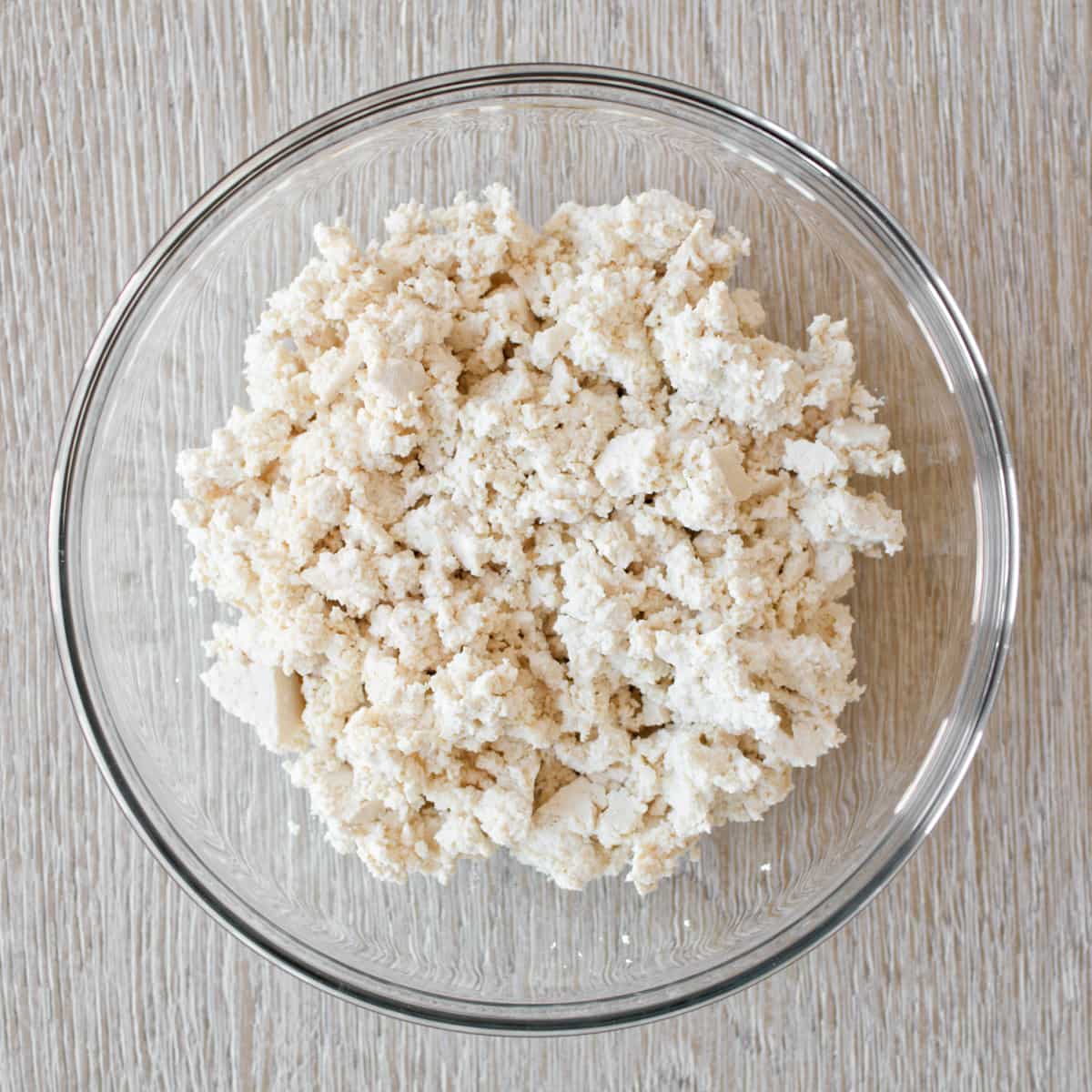Crumbled tofu in a large glass bowl.