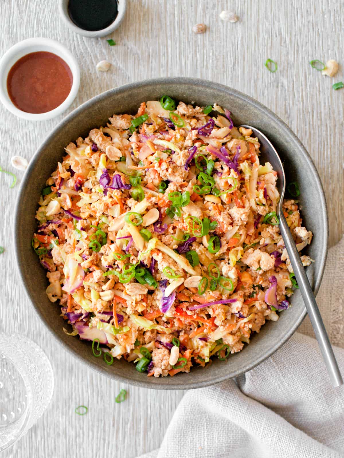 Egg roll in a bowl with coleslaw mix and sauces on the side.